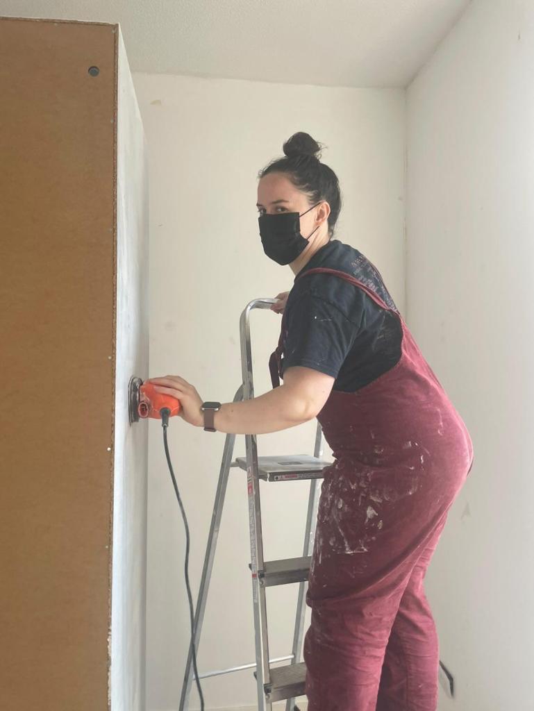 Me, in my DIY dungarees, on a ladder sanding the side of the wardrobe