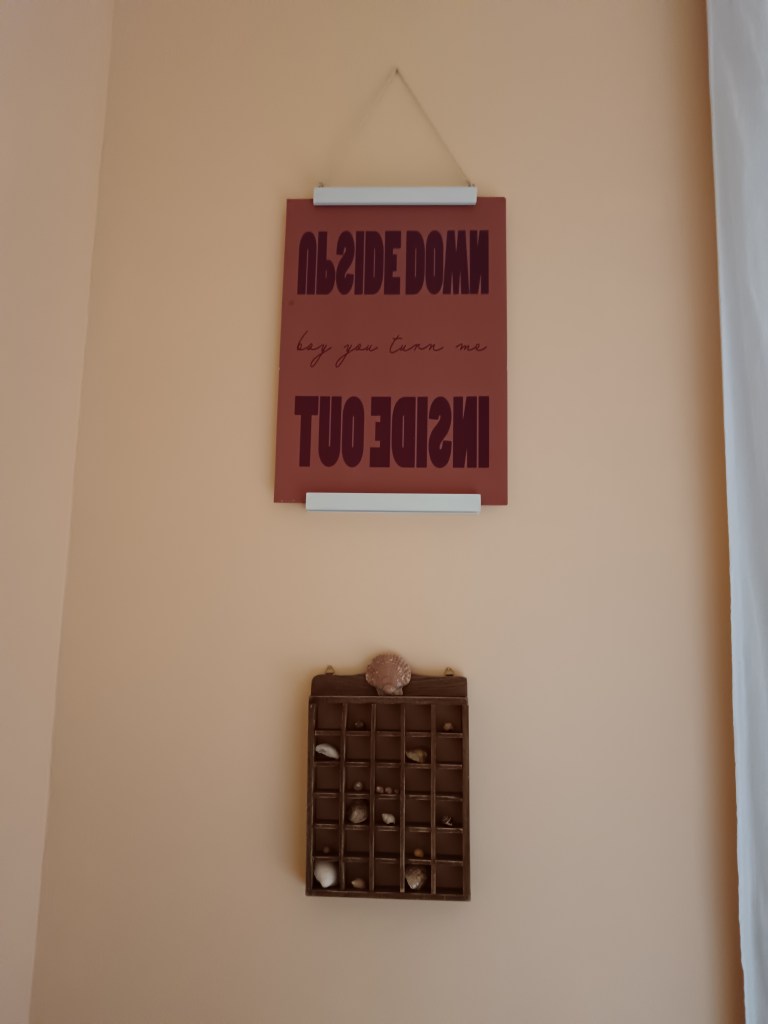 A hanging frame shows art that says upside down, boy you turn me inside out, underneath I hang a trinket shelf with lots of little compartments to hold my shell collection
