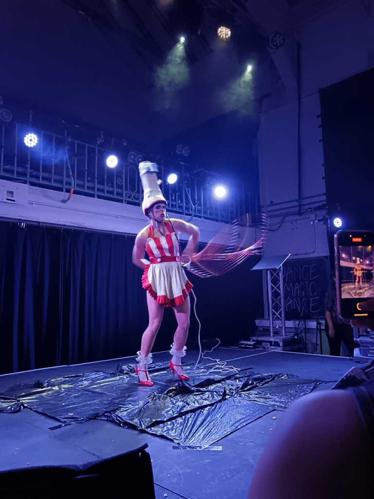 A woman dressed as a cinema worker has popcorn on her head and spins several hula hoops