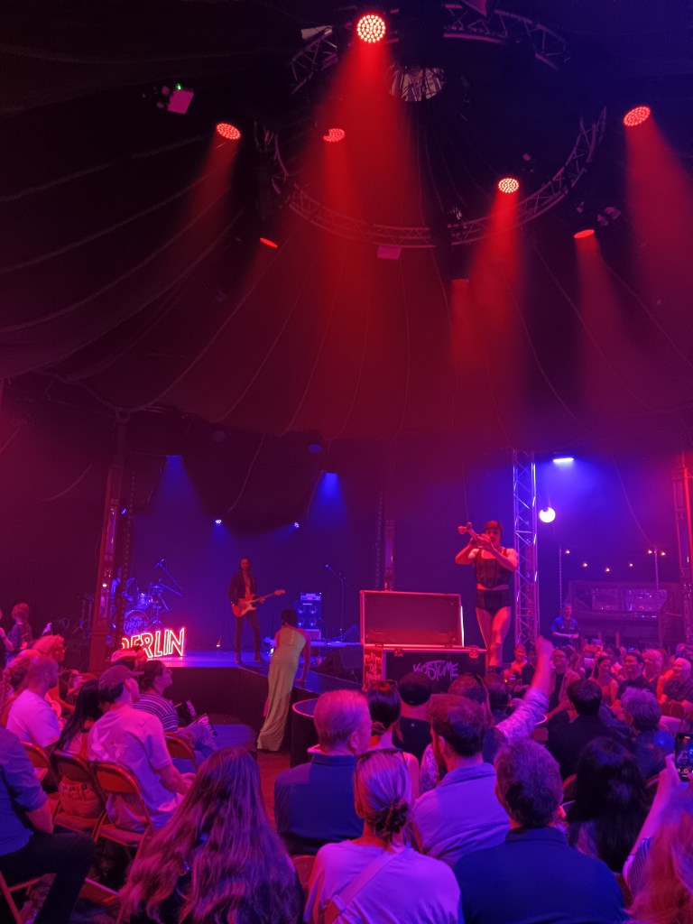 Inside a cabaret tent, red light shines down