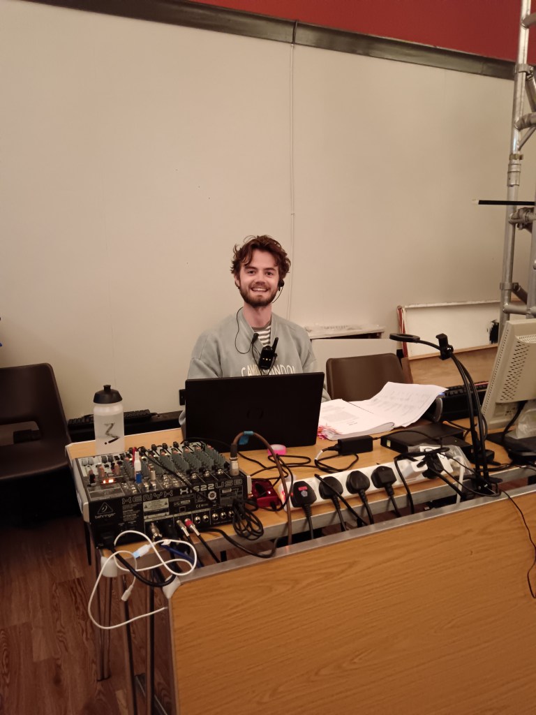 Kit smiles sitting behind the tech desk