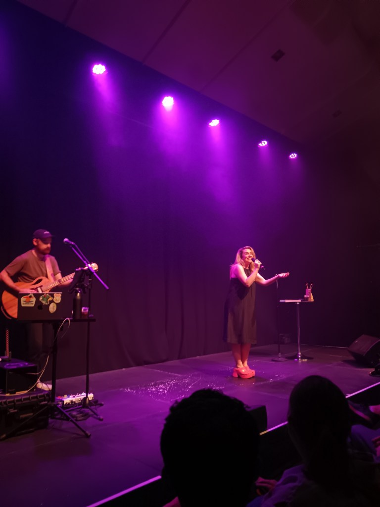 Michelle smiles and sings into a mic