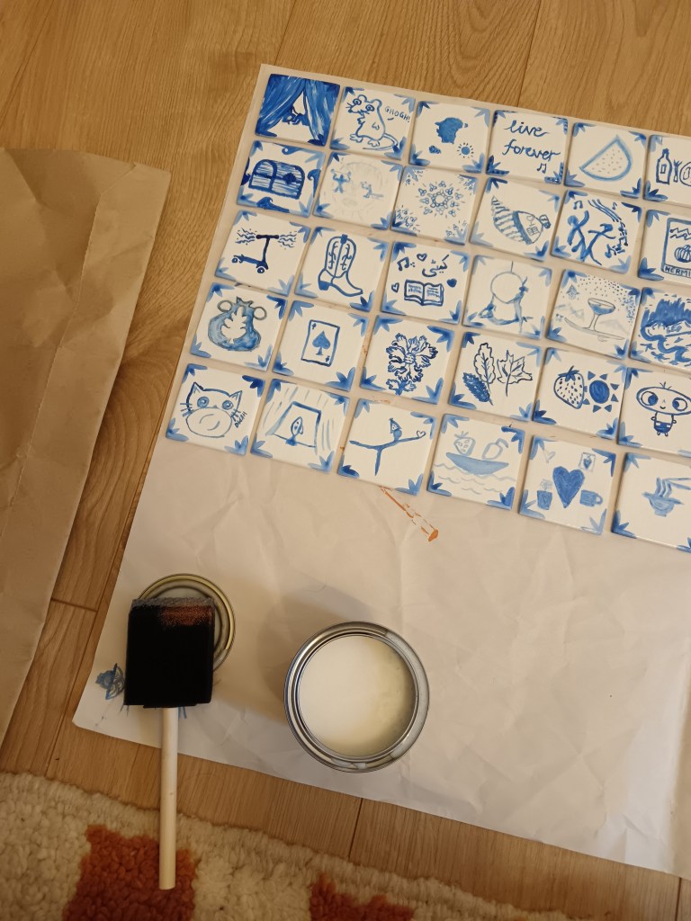 A bunch of tiles with little pictures laid out for top coating