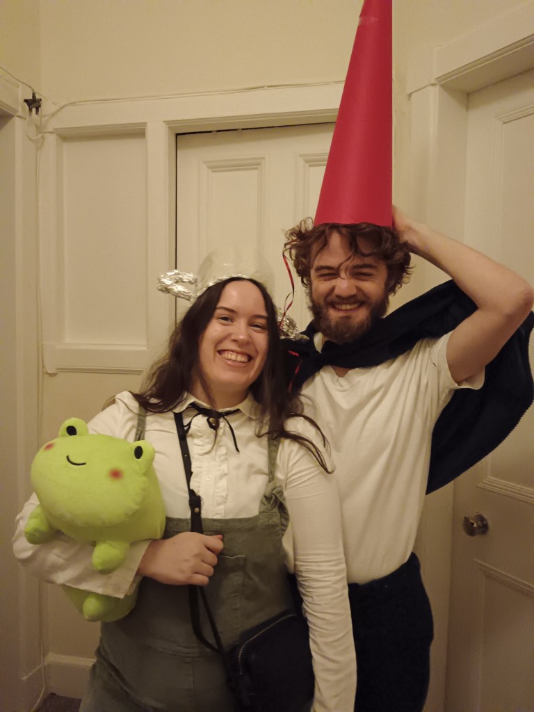 Kit and I dressed as Over the Garden Wall characters, I have a teapot hat and hold a little frog, Kit has a capee and a tall red cone hat