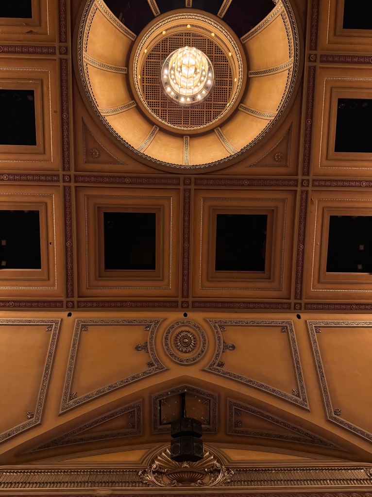 The golden ceiling and chandelier of a theatre
