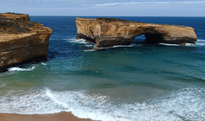Waves come into shore with large rocks standing in it