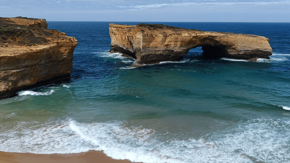 Waves come into shore with large rocks standing in it