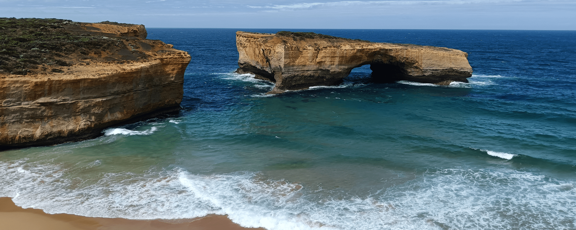 Waves come into shore with large rocks standing in it