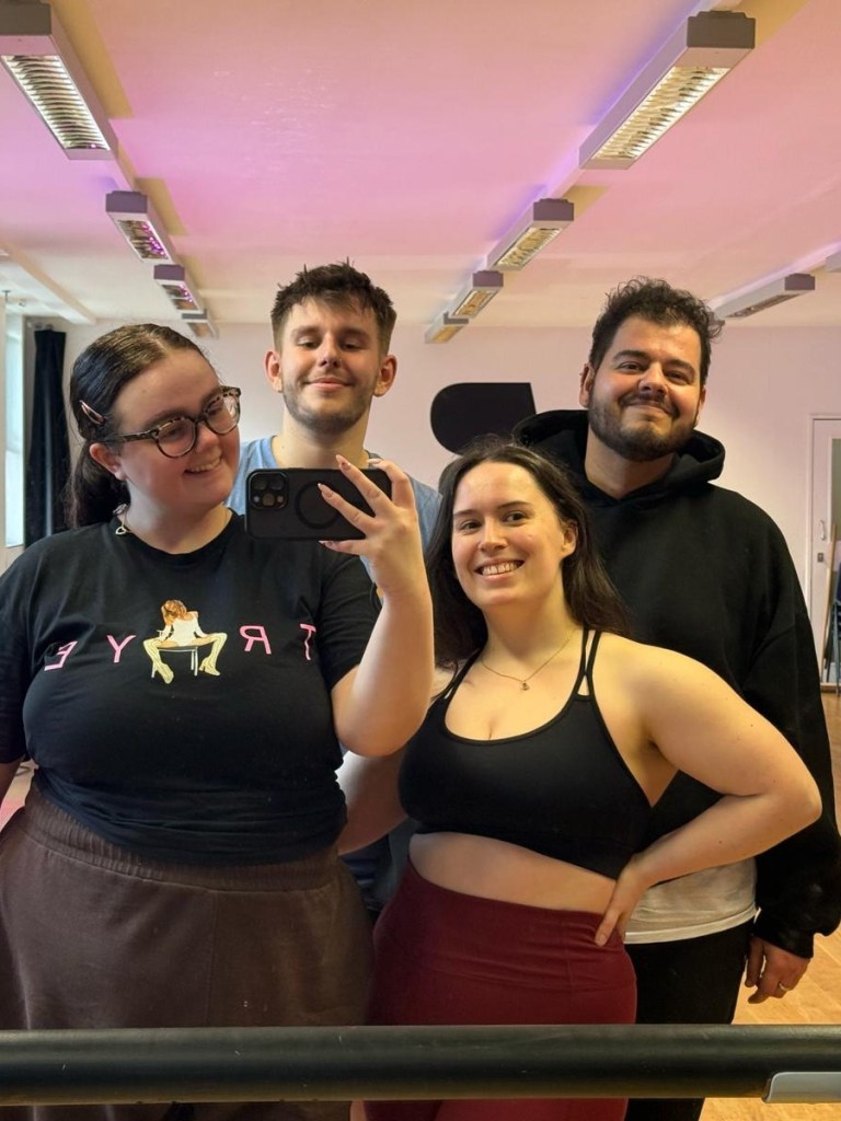 A group smile in the dance studio mirror