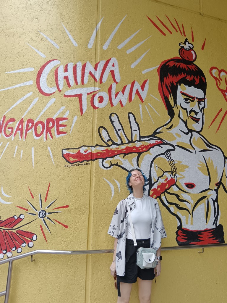 Ejay smiles in front of a painted wall that says China Town