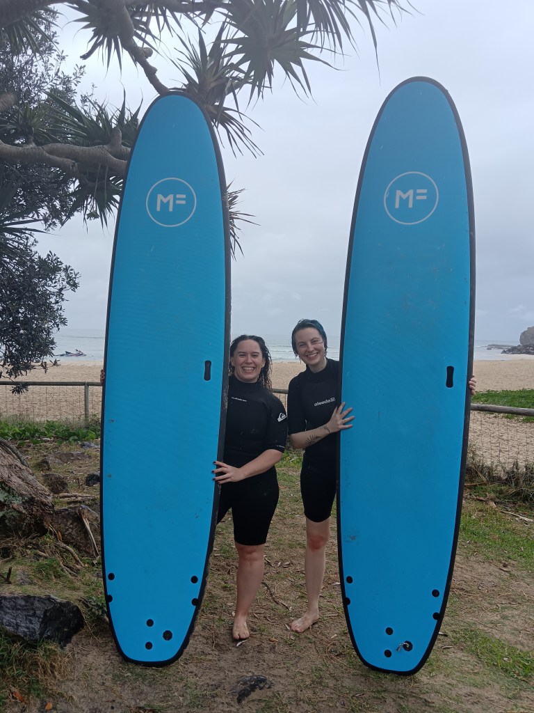 Ejay and I hold our surfboards and smile
