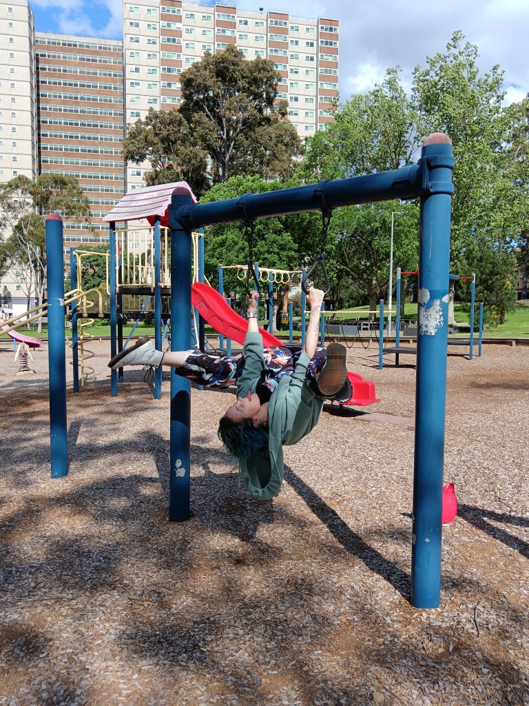 Ejay hanging upside down in a park