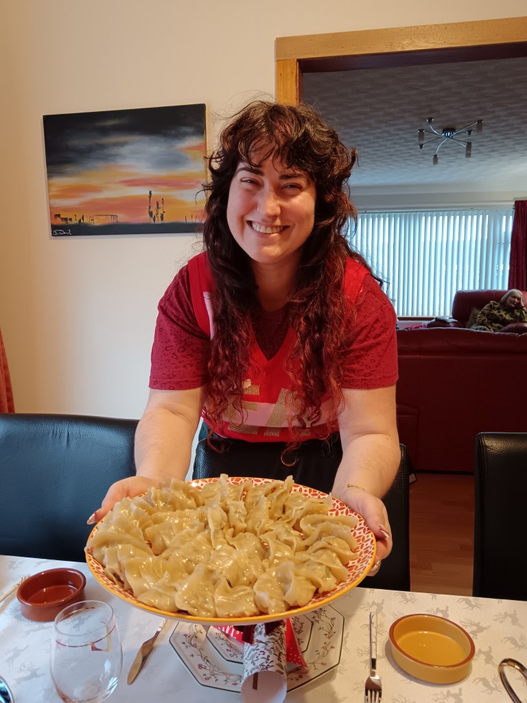 Georgia smiles holding a giant plate of dumplings