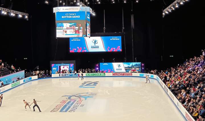 Skaters warm up on a rink with an audience full watching on