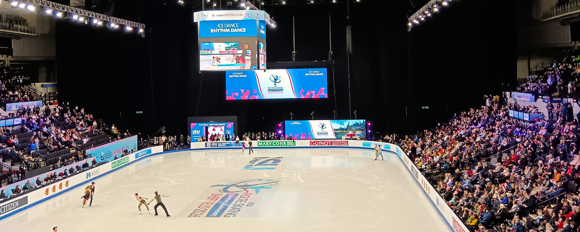 Skaters warm up on a rink with an audience full watching on