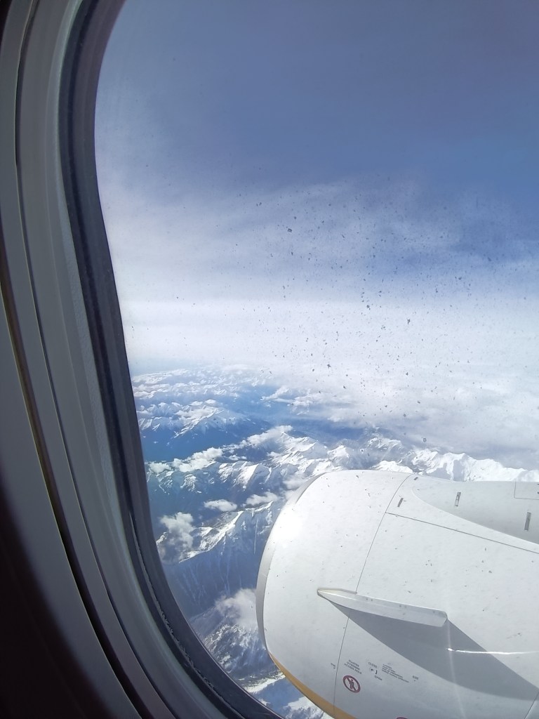 Snow peaked mountains through a plane window