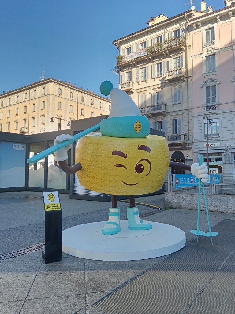 A statue of a big parmesan wheel holding skiing gear