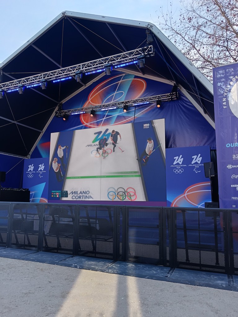 A stage with a big screen showing curling from the Winter Olympics