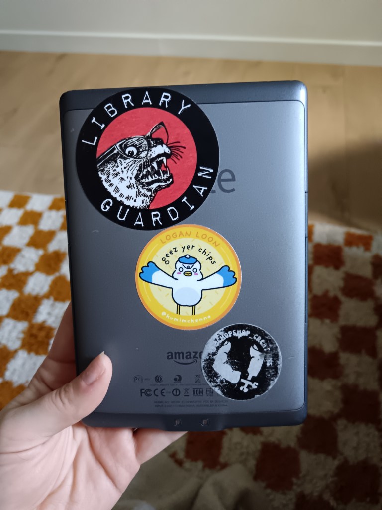 Stickers on the back of my Kindle shows an aggressive seal labelled Library Guardian, a wee seagull that says geez yer chips and a sticker for my friends model making business