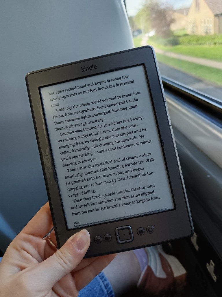 I hold my kindle, reading on the train
