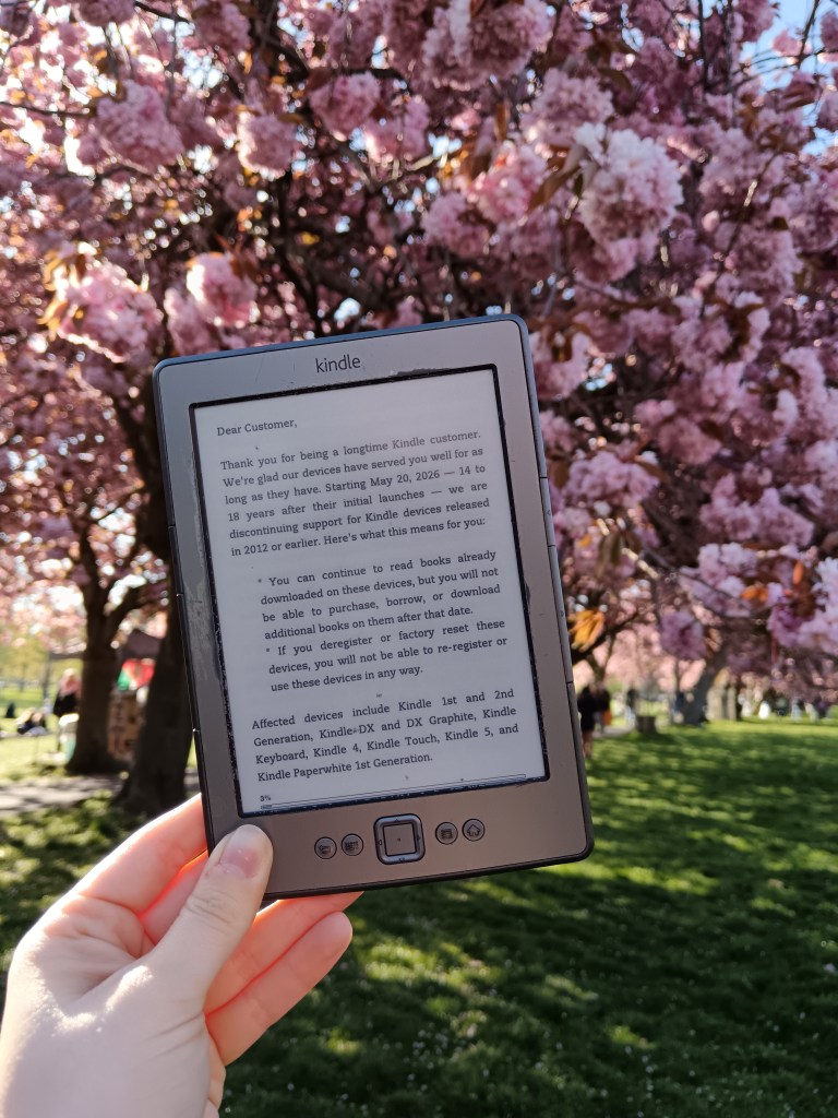 I hold my kindle with the discontinued message on it in front of a cherry blossom tree