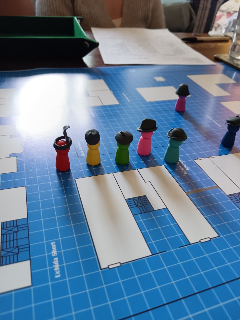A blue print upon which custom player counters in hats stand
