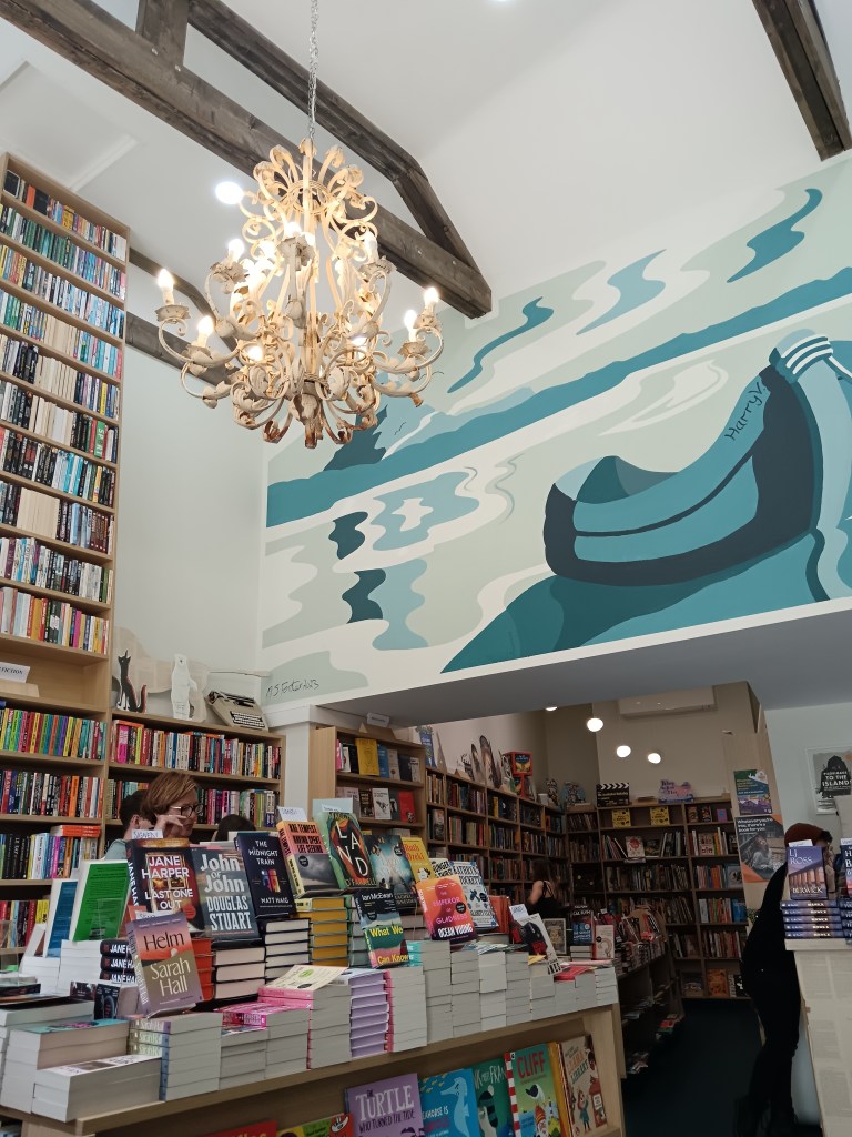 A beautiful bookshop with a beachy mural on the wall