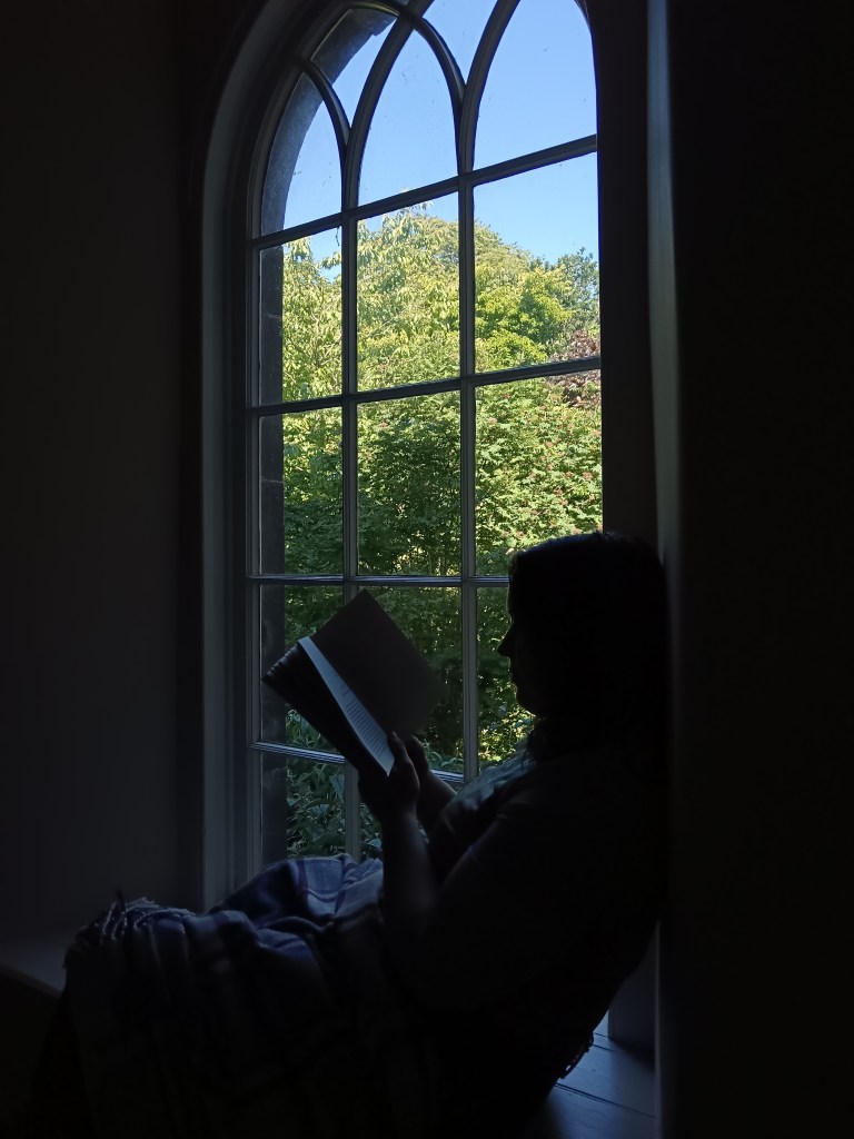 My silhouette against a beautiful window as I read a book
