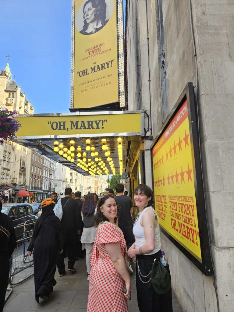 My sister and I smile in front of the marquee for Oh Mary