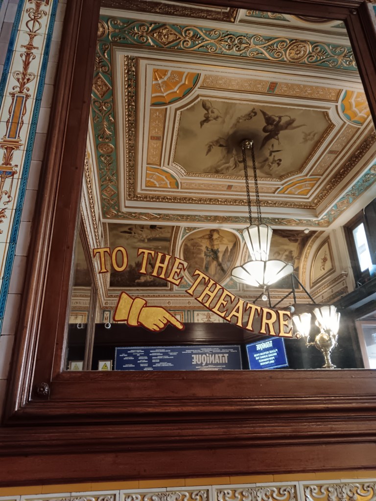 A sign on a mirror points To the Theatre