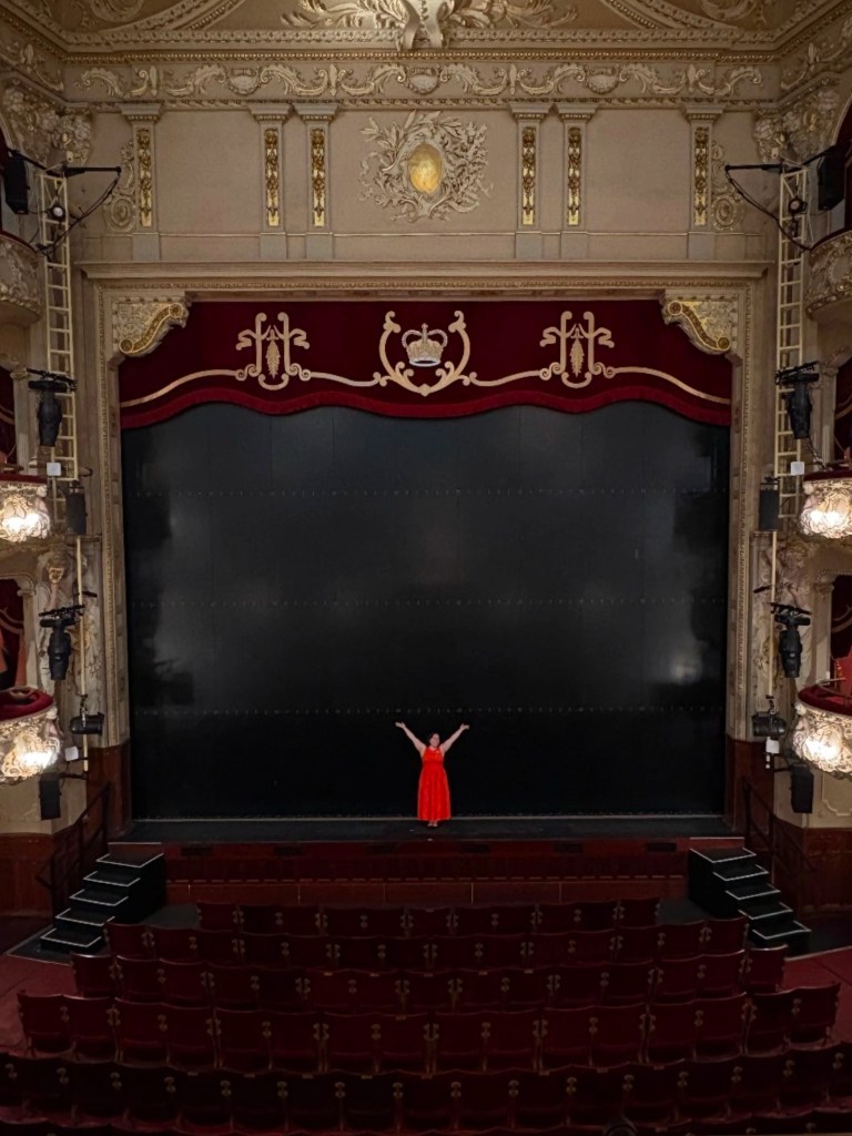 I stand on the King's Theatre stage with my arms raised