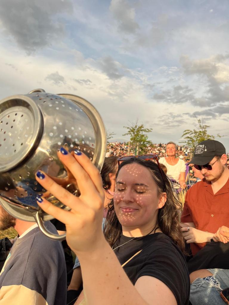 I smile holding a colander in front of my face to let the eclipse light through
